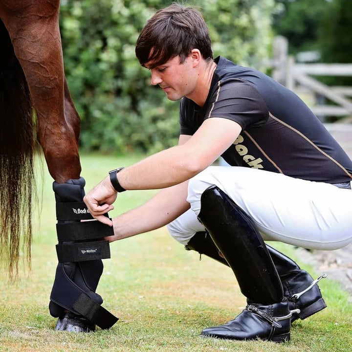 Back On Track Royal Quick Wraps being applied to a horse's leg by a person wearing equestrian gear. Ideal for reducing swelling and providing leg therapy.