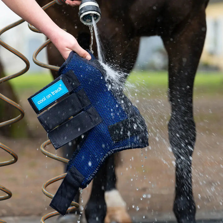 Cool On Track Quick Wrap being rinsed with water, showcasing its reusable, ice-free cooling design for horse leg therapy and care.