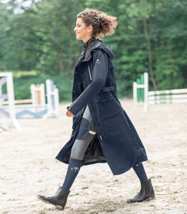 Front view of the ELT Fehmarn Long Riding Raincoat in black, featuring a sleek design with a hood and functional pockets.
