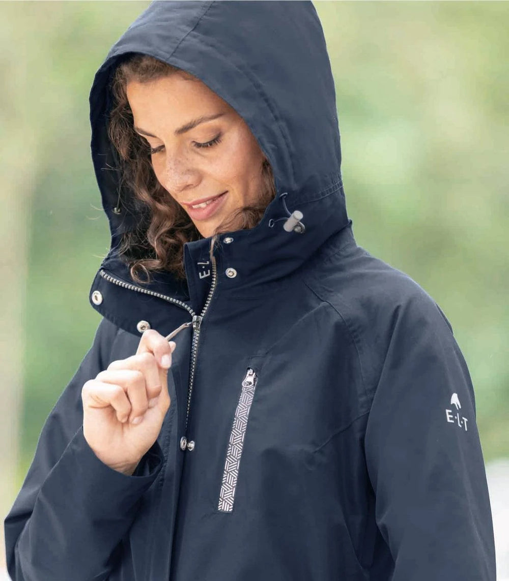 Equestrian rider wearing the ELT Fehmarn Long Riding Raincoat while riding a horse, showcasing its saddle protection and functional design.