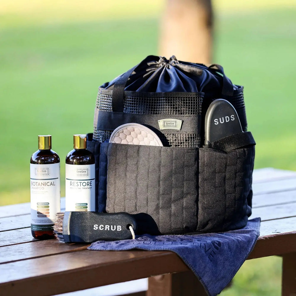 Horse grooming bag on a wooden table with grooming tools, bottles labeled 'Botanical' and 'Restore,' and a towel, ideal for horse care.