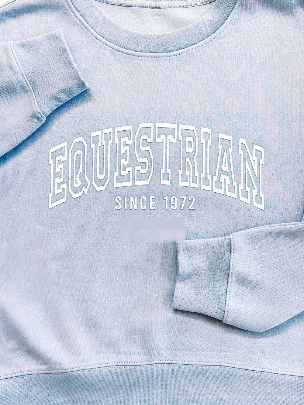Close-up of light blue Limited Edition Equestrian Sweatshirt showcasing raised embossed 'Equestrian Since 1972' text.