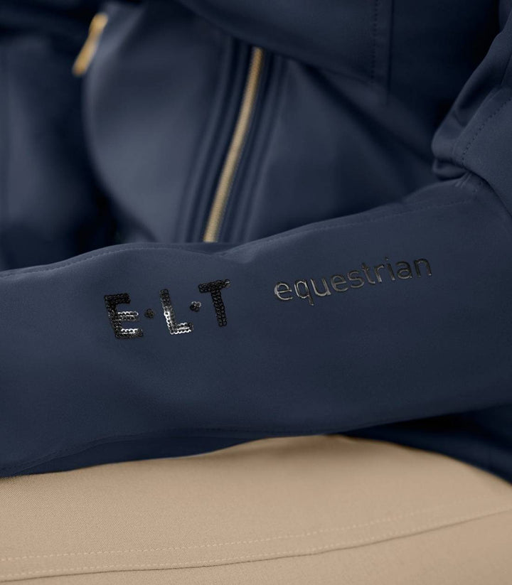 Detailed view of the ELT Luxemburg Softshell Jacket sleeve with embroidered ELT equestrian branding in black and gold.