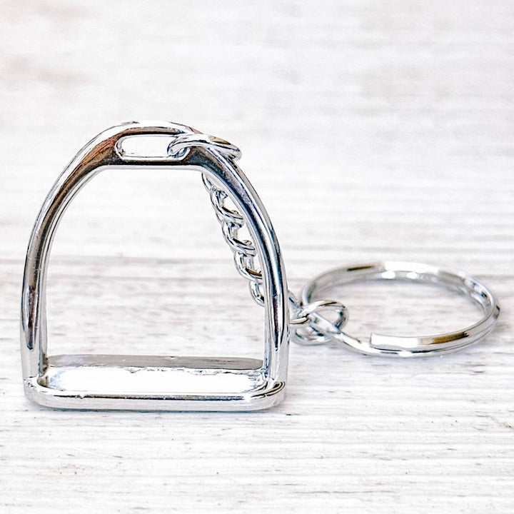 Side view of a silver stirrup keychain highlighting the smooth metallic stirrup charm and sturdy keyring.
