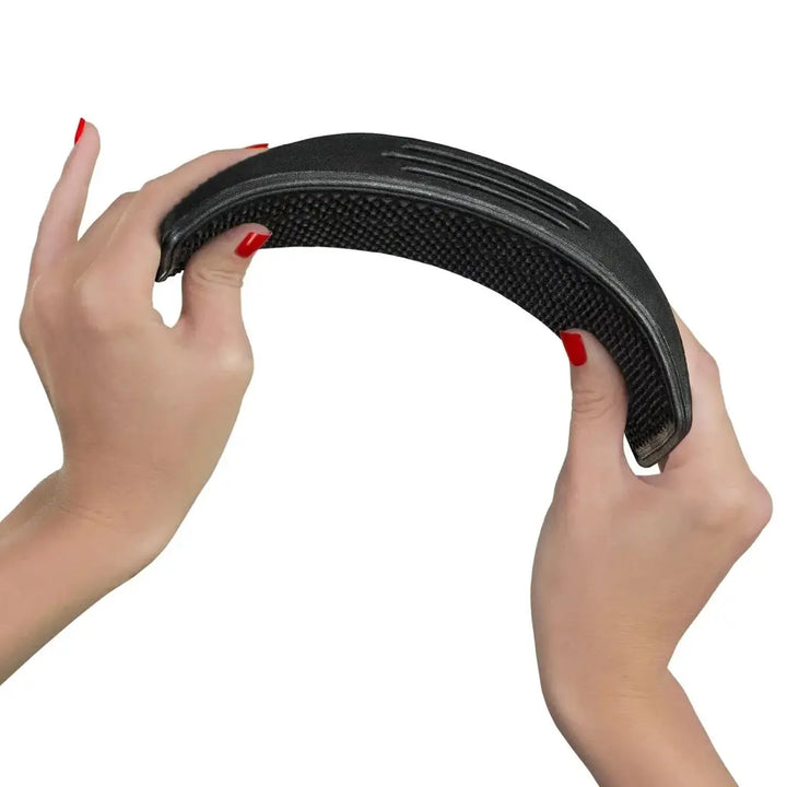 Flexible black curry comb being bent by hands, designed for effective horse grooming and easy handling.