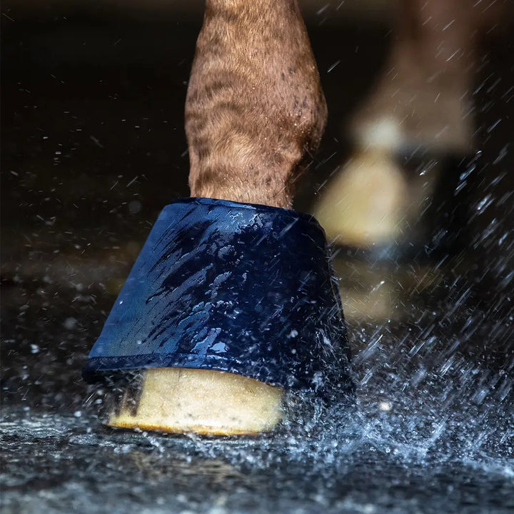 Waldhausen Water Bell Boots in use, protecting a horse's hoof while splashing water to maintain hydration and prevent dryness.