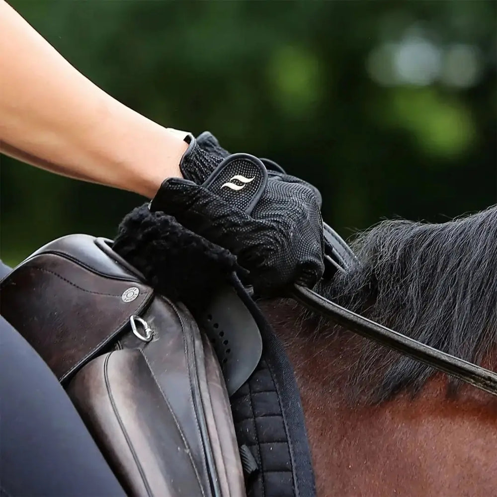 Rider wearing black therapeutic horse riding gloves while holding reins, showcasing grip and functionality during horseback riding.